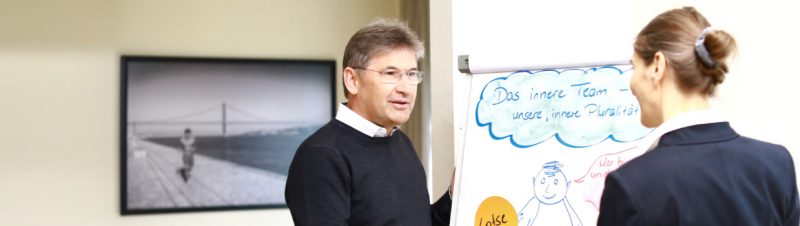 Uwe Arand mit einer Klientin am Flip Chart Uwe Arand am Flip Chart